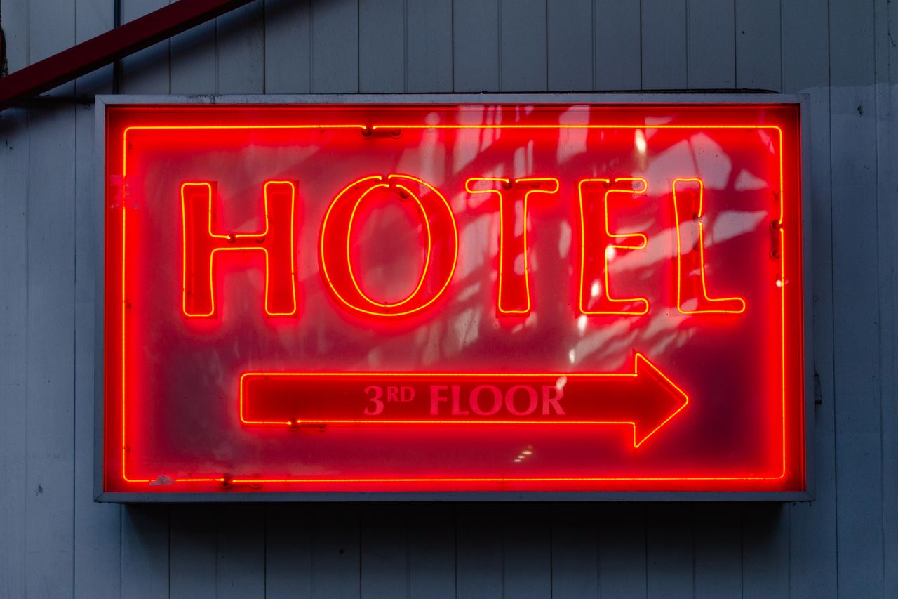 Close-up of a neon hotel sign indicating the 3rd floor, vibrant in red.
