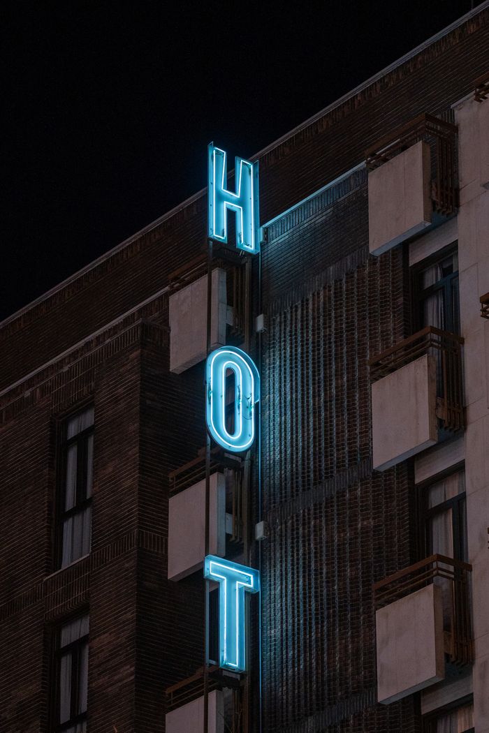 Vertical shot of a neon hotel sign on a building in Madrid at night, capturing urban nightlife.